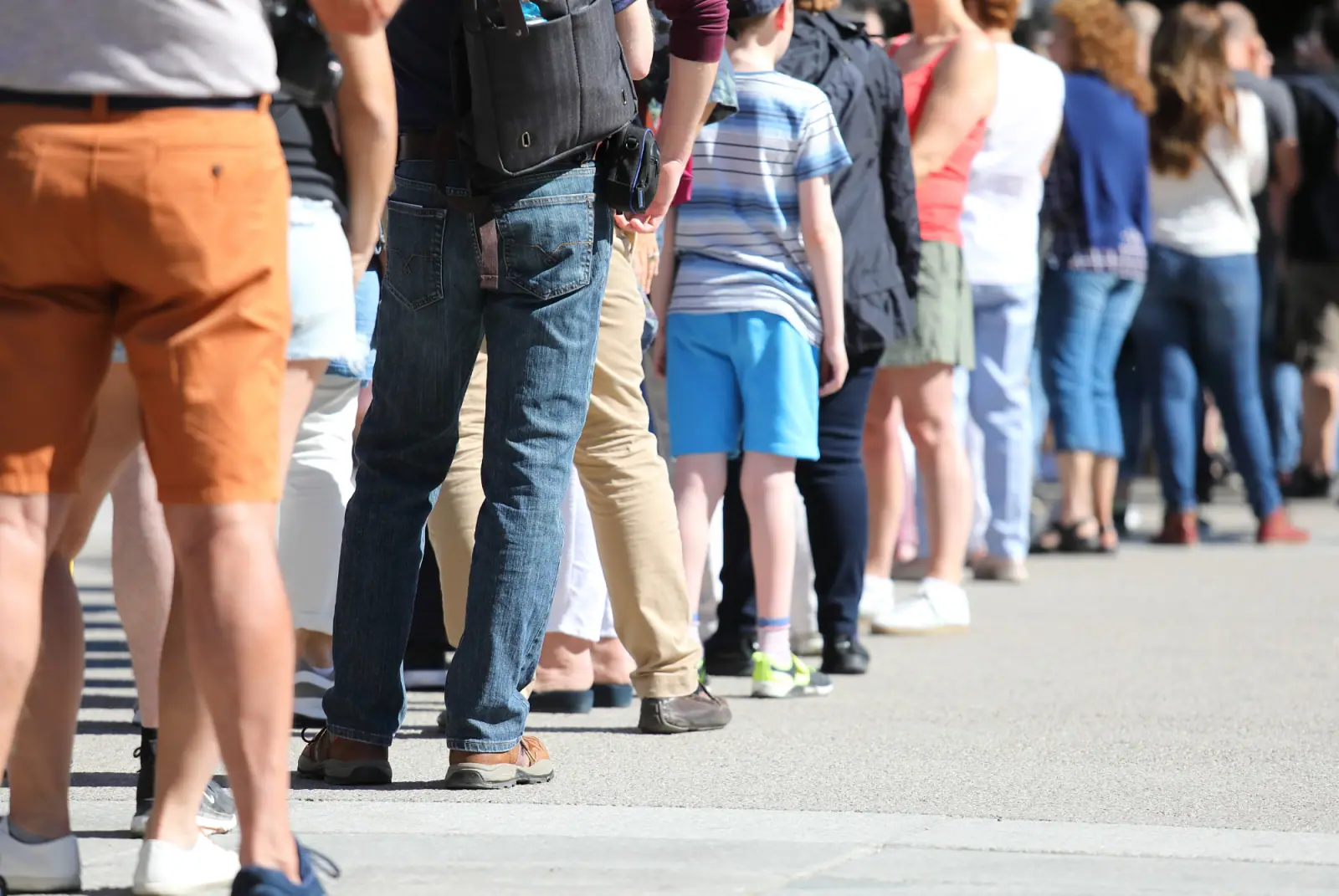 Menschen stehen in einer langen Warteschlange im Freien hintereinander an