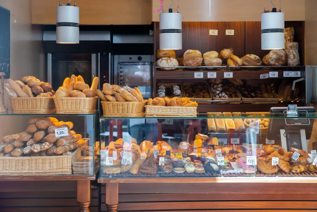 Vielfältiges Sortiment an frischem Brot, Brötchen und Gebäck in einer Bäckereiauslage mit Preisschildern