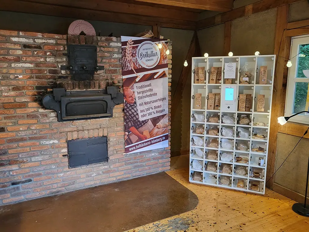 Weiße Marktbox neben einem traditionellen Steinofen für den Verkauf von frischem Brot und Gebäck