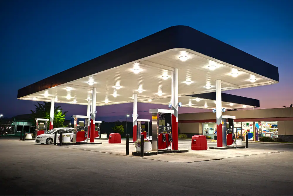 Hell beleuchtete Tankstelle bei Nacht mit modernen Zapfsäulen und einem angrenzenden Shop-Gebäude
