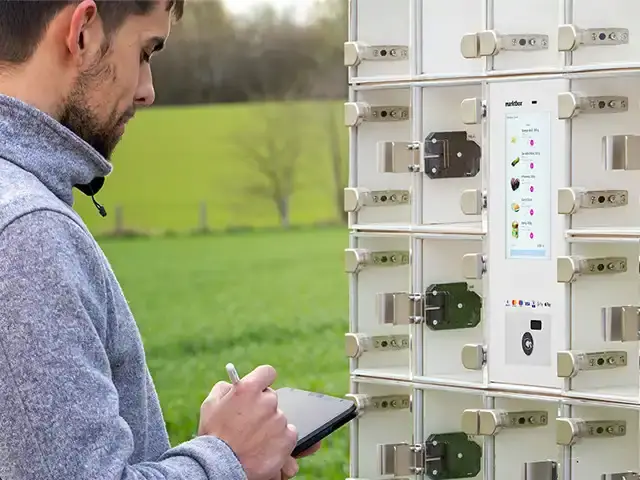 Mann nutzt Tablet vor einem marktbox Verkaufsautomaten mit Touch-Display und Glasfächern im Freien