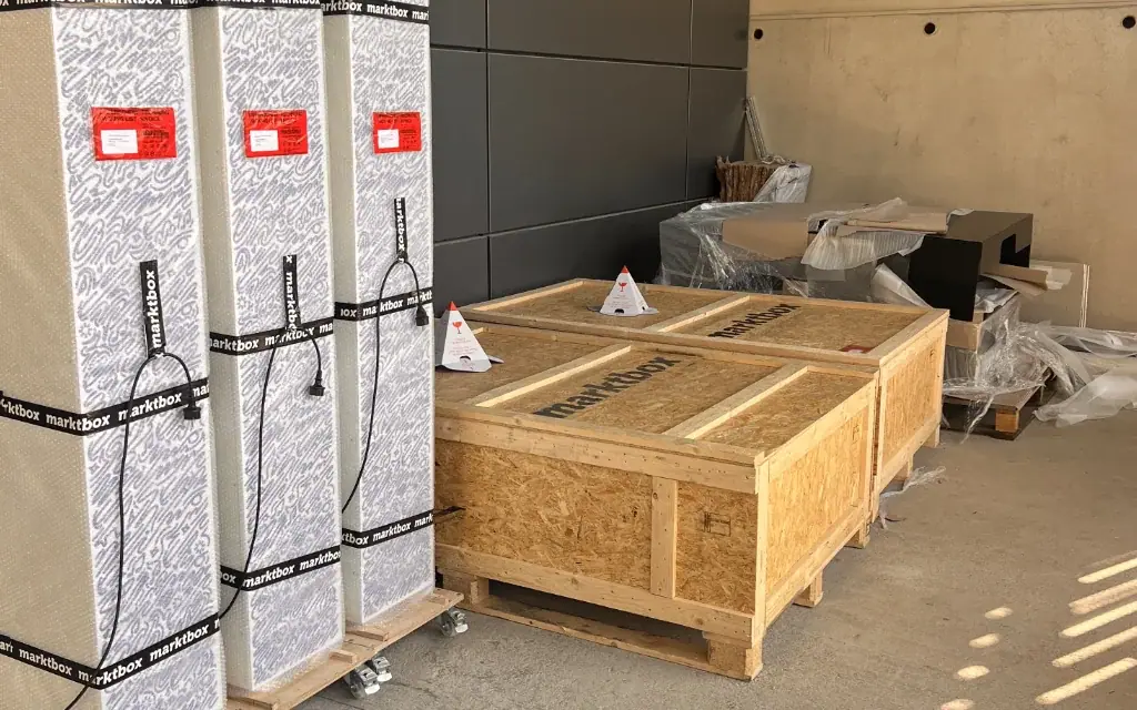Drei verpackte marktbox-Automaten und zwei große hölzerne Transportkisten stehen versandbereit