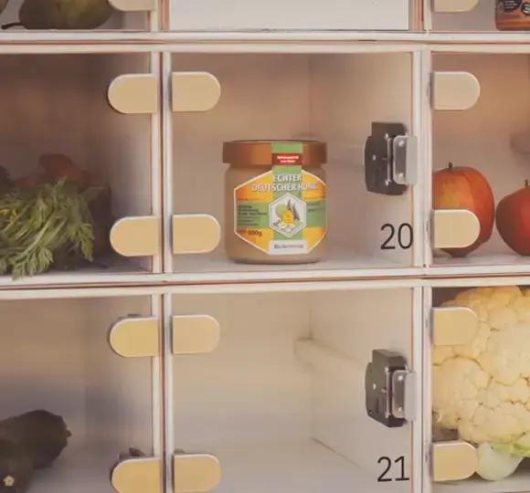 Ein Honigglas in Fach 20 der marktbox neben frischem Obst und Gemüse in den benachbarten Fächern