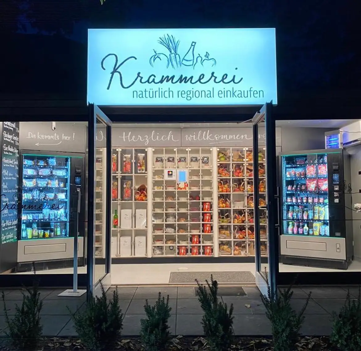 Hell erleuchteter Verkaufsautomatenshop mit regionalen Lebensmitteln in verschiedenen Warenautomaten bei Nacht