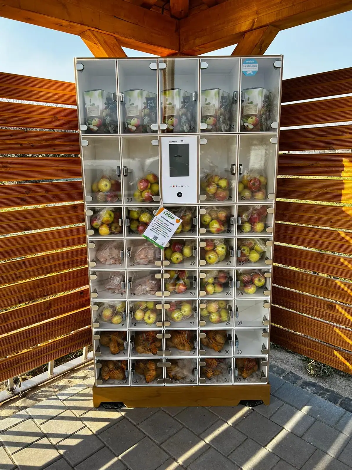 Moderner marktbox Verkaufsautomat mit Glasfächern für regionale Produkte wie Äpfel in einer Holzkonstruktion